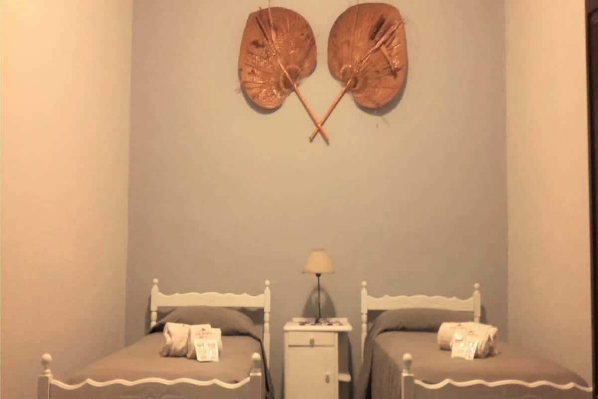 Un dormitorio con dos camas individuales, una mesita de noche y una lámpara.