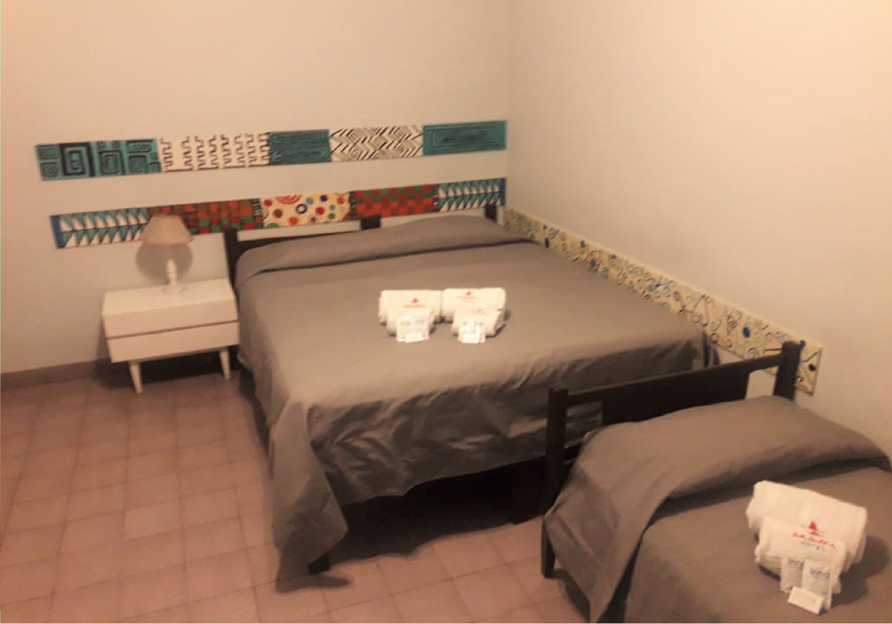 A bedroom with a bed, a nightstand, and a bedside table.