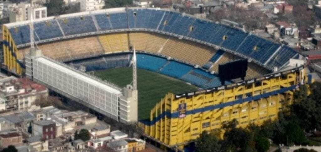 Een groot stadion met meerdere rijen tribunes en een middenveld.