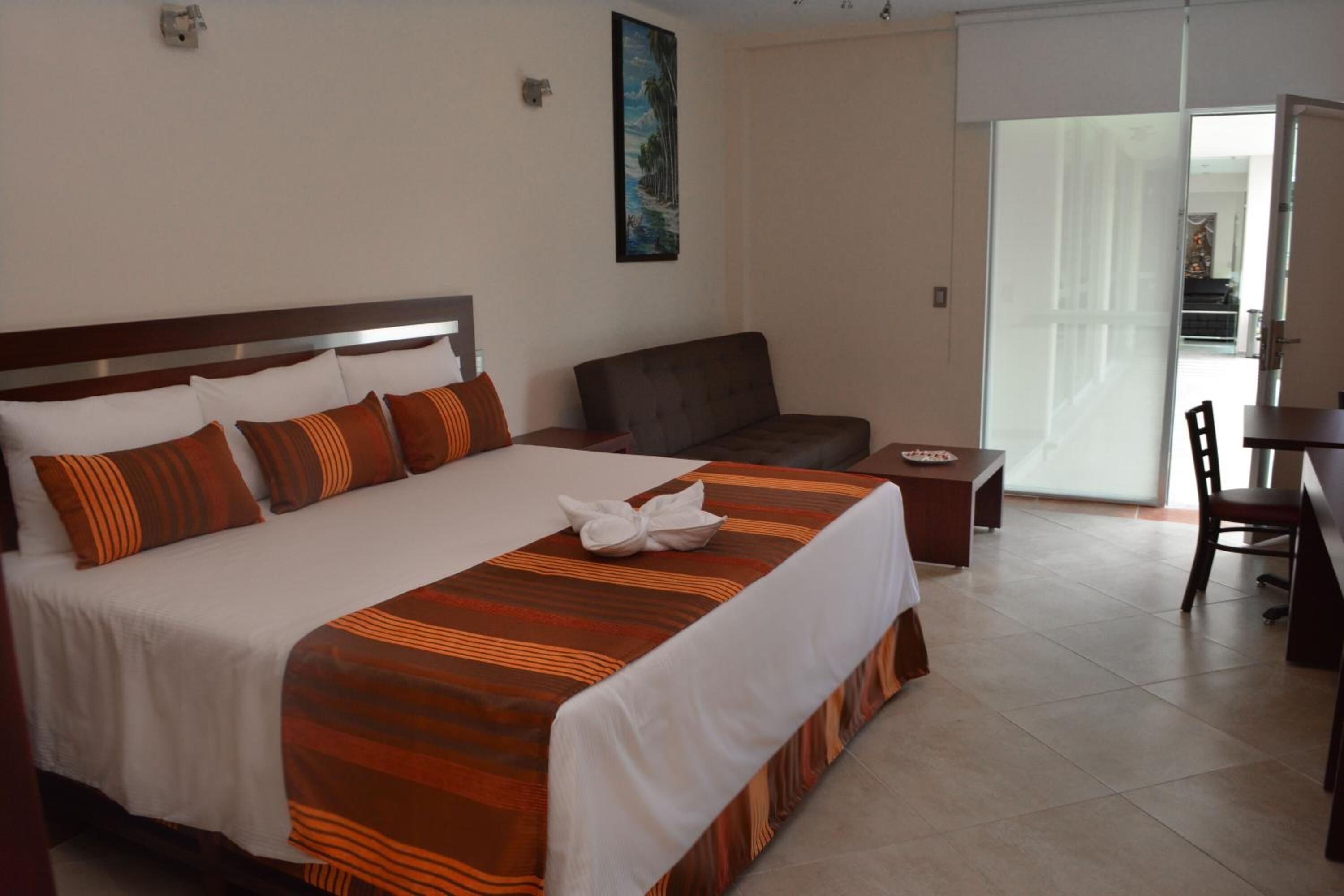 Ein Hotelzimmer mit einem großen Bett, einer Couch, einem Schreibtisch und einem Sessel.