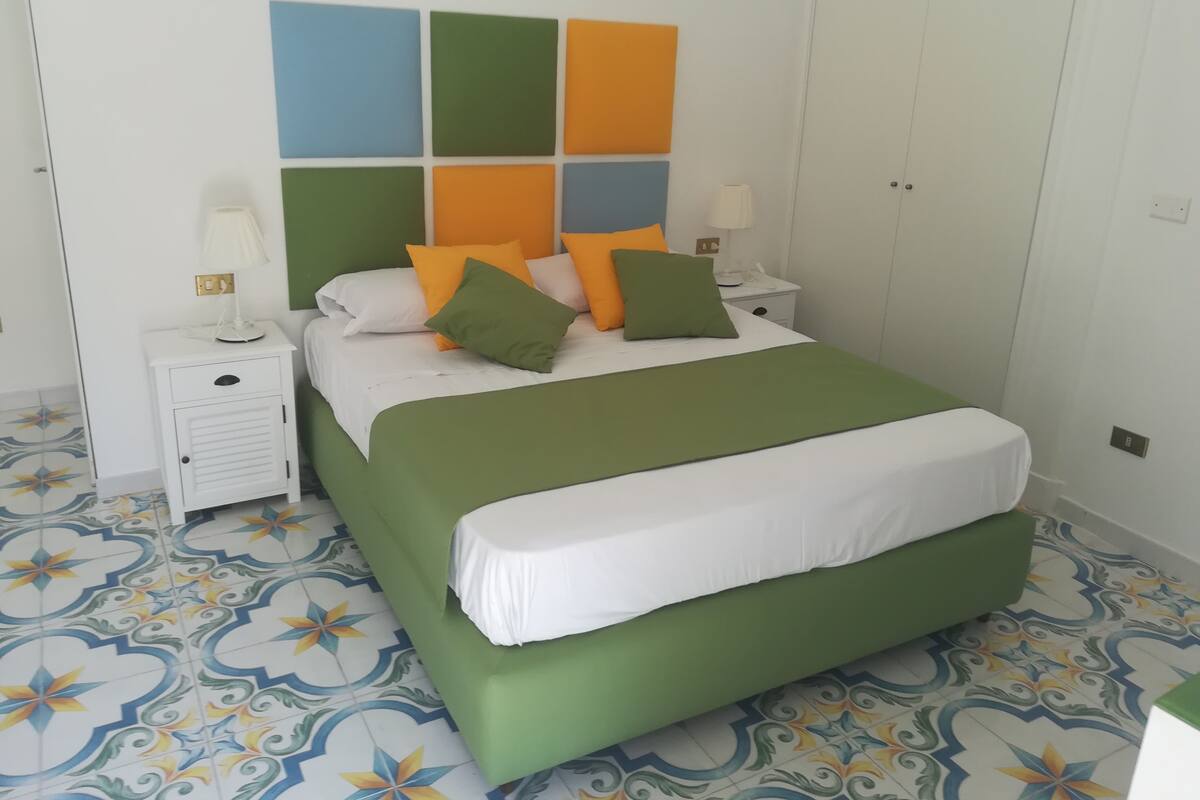 A bedroom with a bed, nightstands, and a patterned floor.