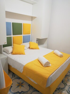Une chambre d’hôtel avec un lit, des oreillers, une table de chevet et une lampe.