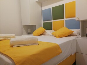 Une chambre d’hôtel avec un lit, une table de chevet et un mur orné de panneaux de couleurs.