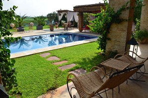 Una piscina al aire libre, sombrillas, sillones reclinables de piscina