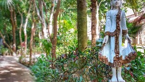 A statue of a figure in traditional attire, surrounded by lush greenery and trees. - Xolumado Inspiration Village by Karisma (Playa del Carmen)