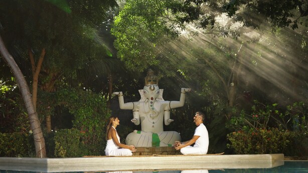 Two people meditating by a pool with a statue in the background. - Xolumado Inspiration Village by Karisma (Playa del Carmen)
