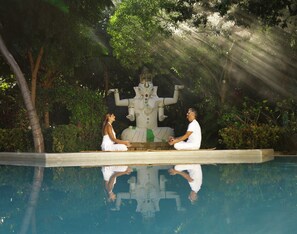 Two people meditating by a pool with a statue in the background. - Xolumado Inspiration Village by Karisma (Playa del Carmen)
