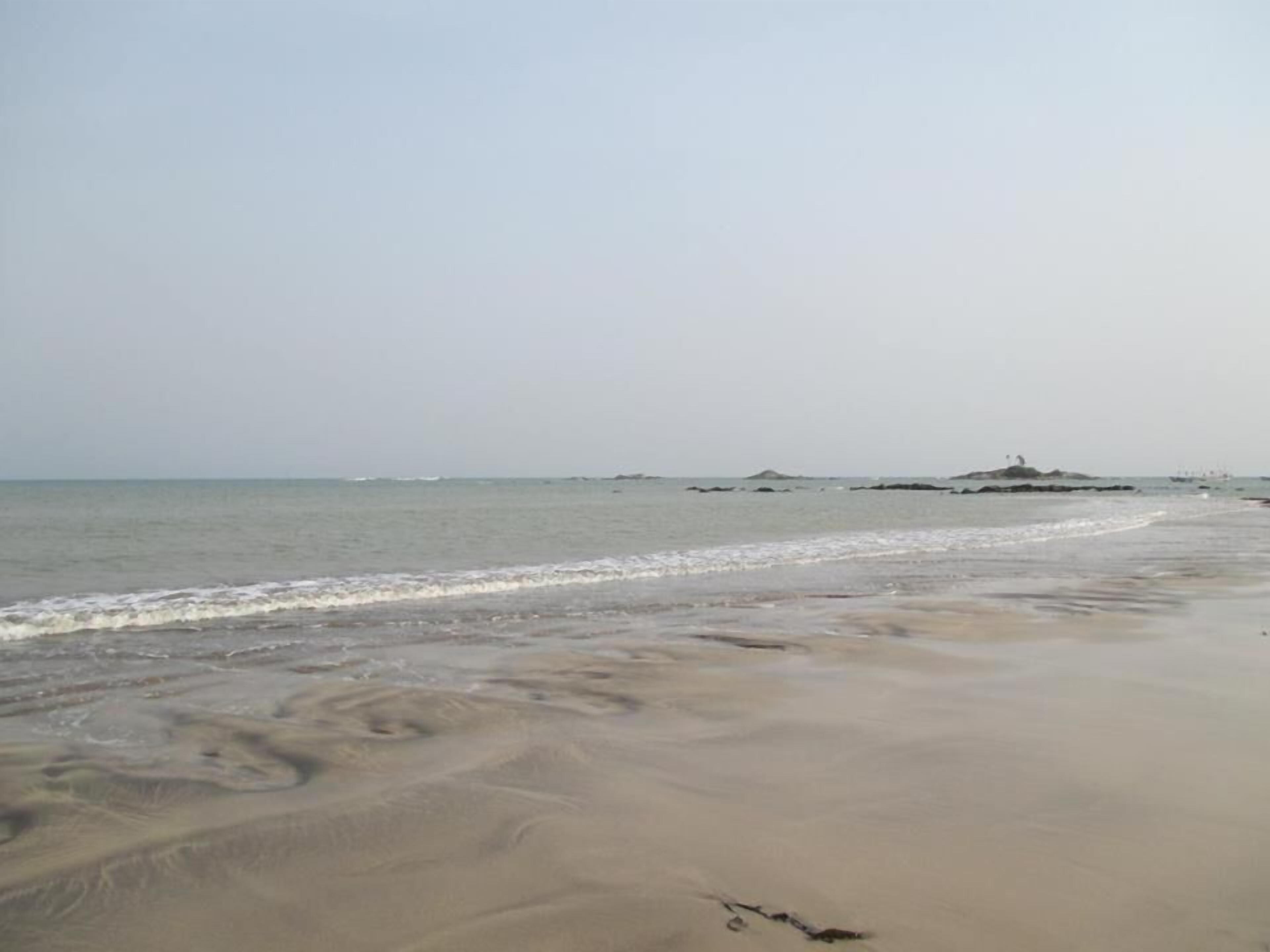 A beach with a sandy shore and calm water.