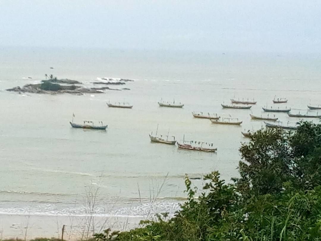 Une mer calme, avec plusieurs bateaux ancrés au loin.