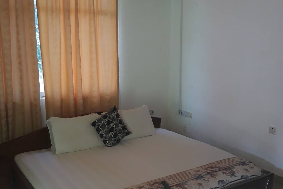 Een slaapkamer met een bed, gordijnen, een airconditioning en een radiator.