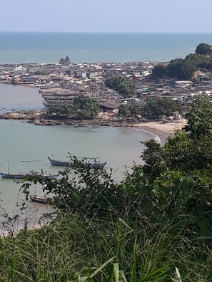 A coastal town with boats docked near the shore, surrounded by dense vegetation and buildings.