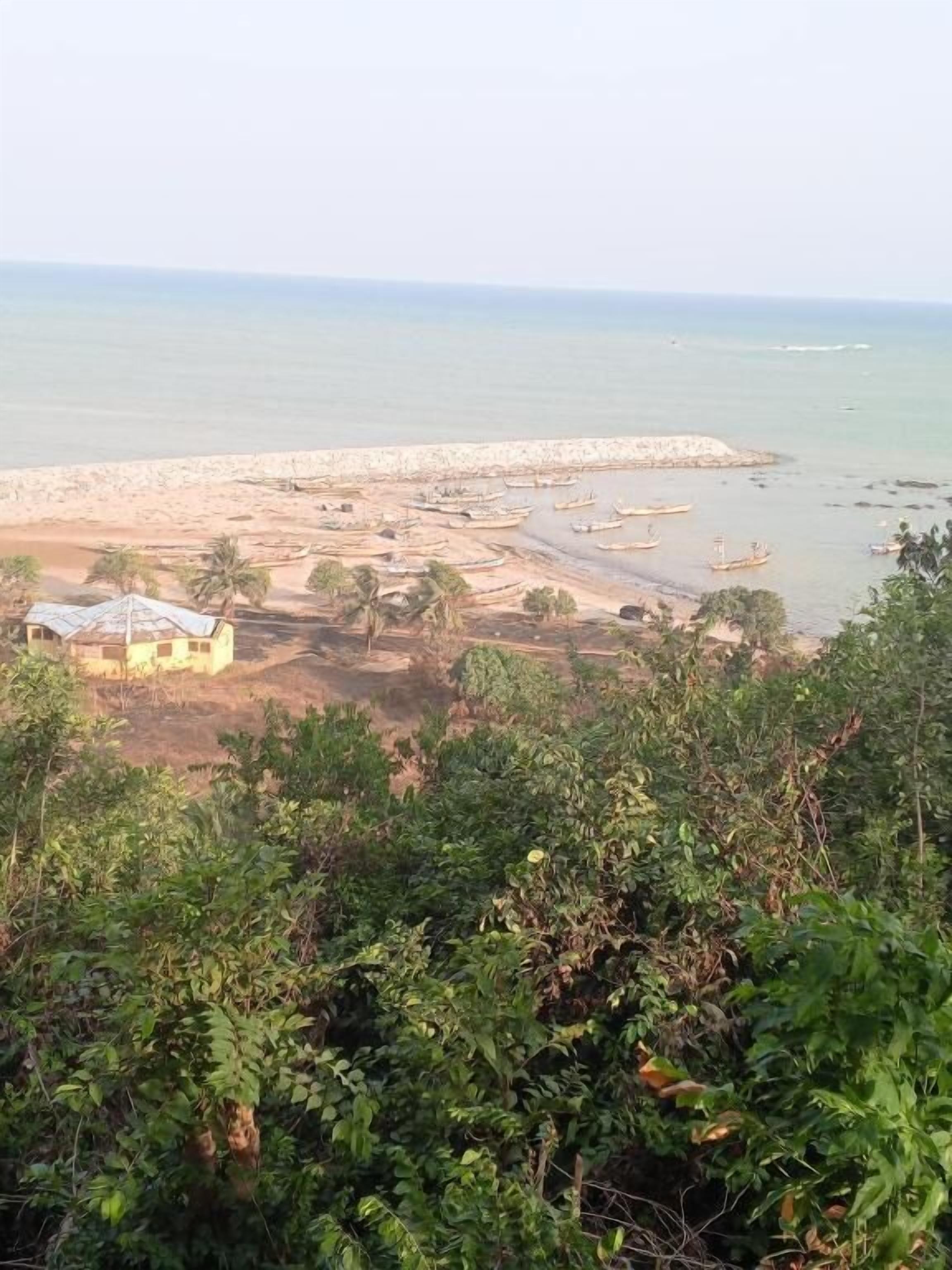 Eine Küstenlandschaft mit Strand, Booten und einem kleinen Gebäude.