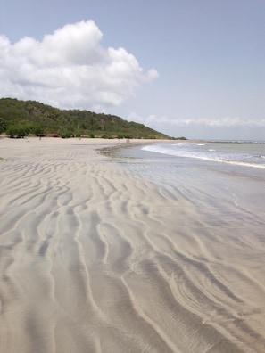 A sandy beach with gentle waves and a forested hill in the background. - Abuesi Beach Resort (Sekondi-Takoradi)