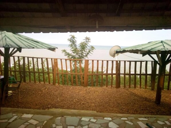 A covered outdoor area with a view of the sea, a wooden fence, and a satellite dish.