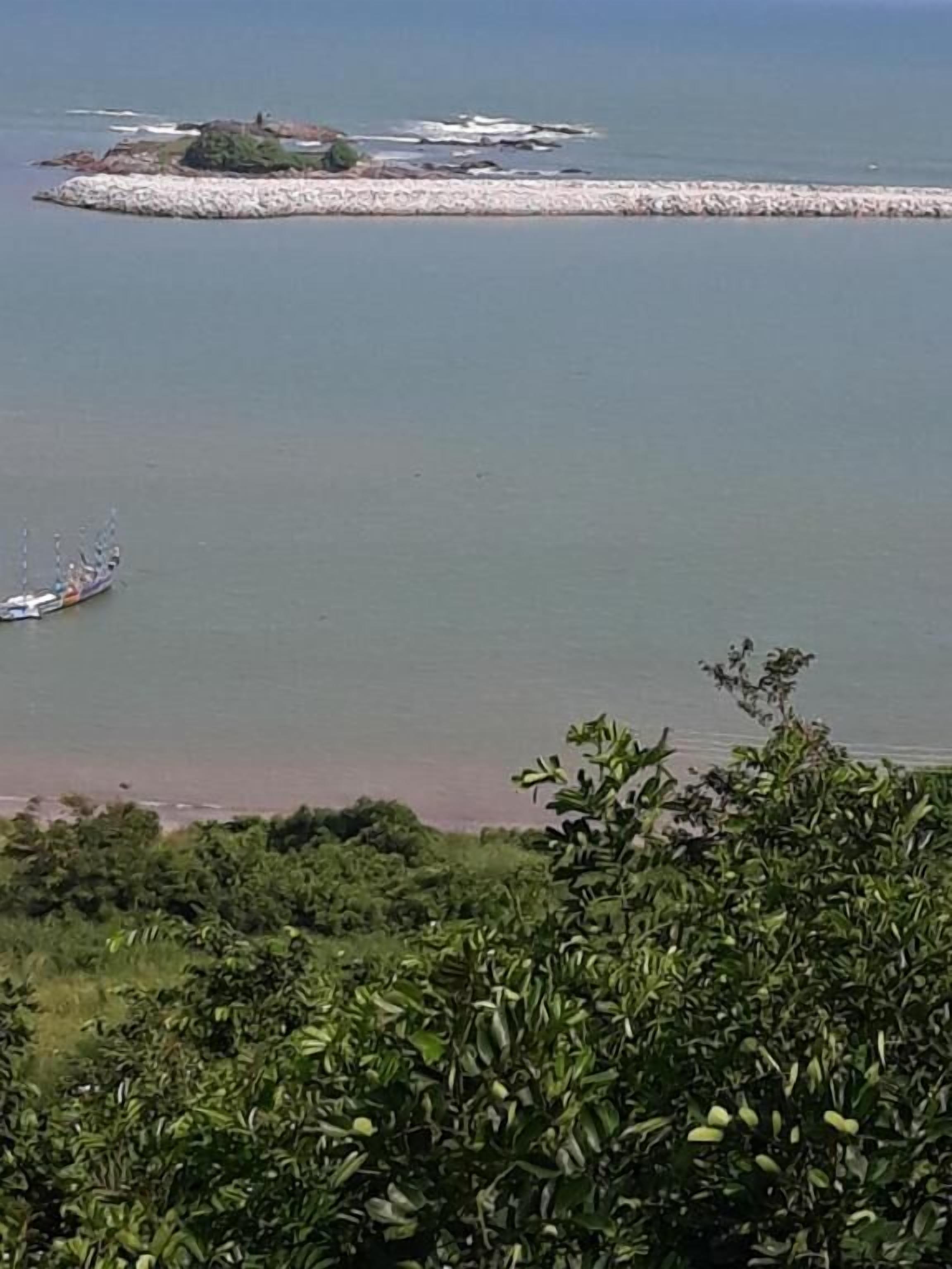 A coastal landscape with a boat on the water and a distant island.