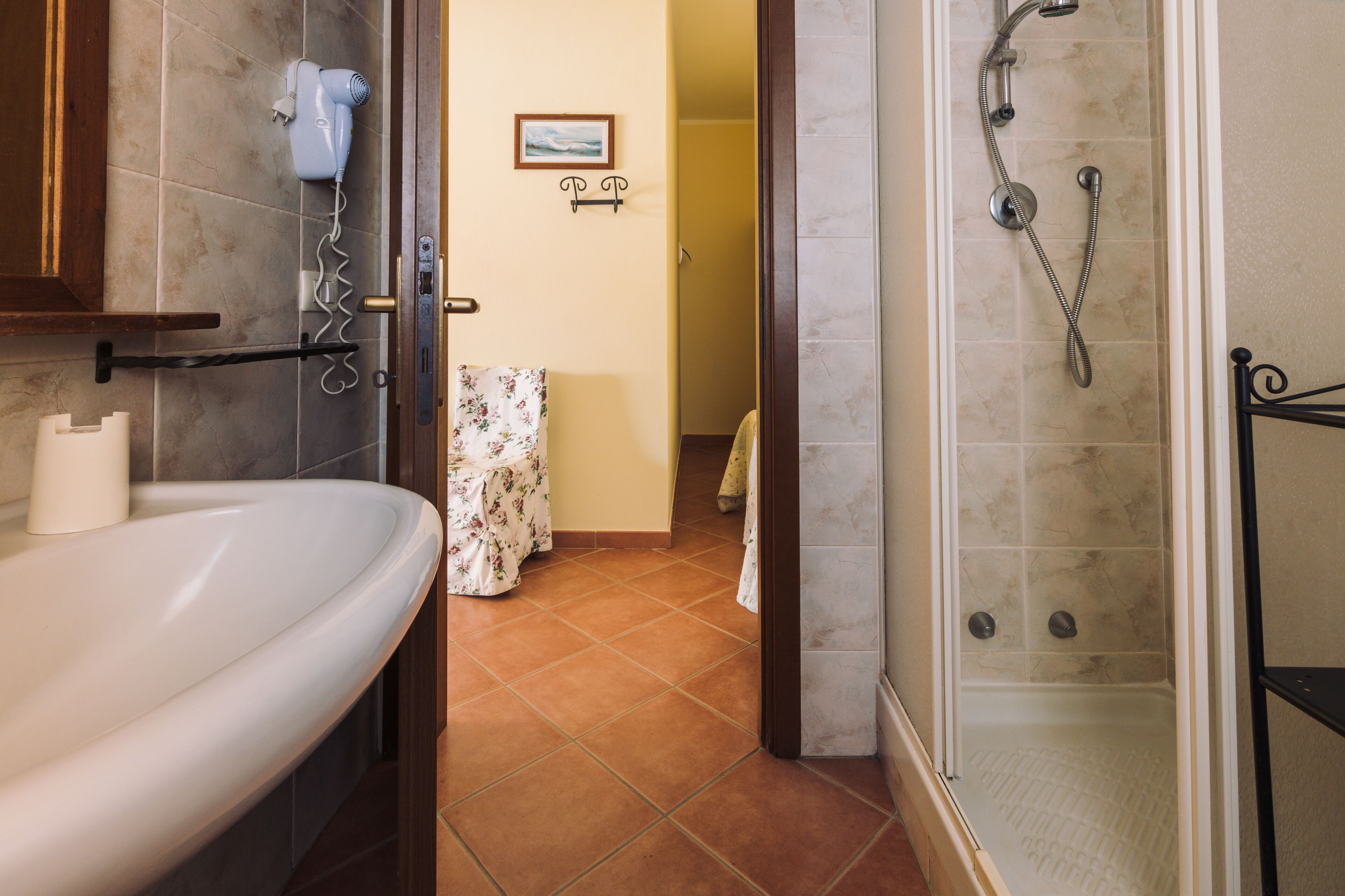 Une salle de bain équipée d’un lavabo, d’un sèche-cheveux, d’une douche et d’un porte-serviettes.