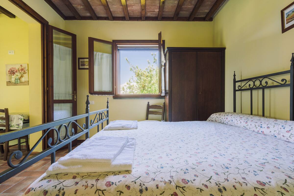 Une chambre à coucher avec un lit, une fenêtre, une chaise et une porte en bois.