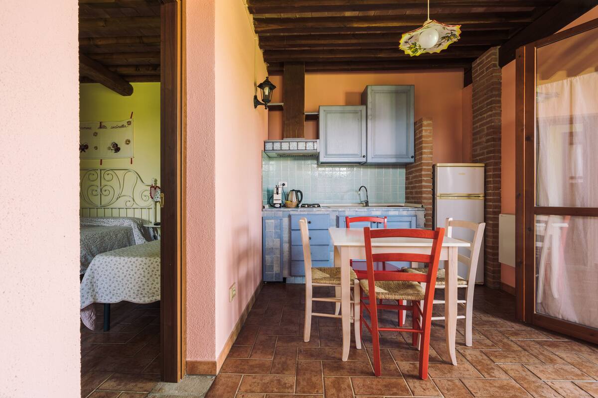 Une cuisine de taille réduite avec des meubles bleus, une table à manger avec des chaises et un réfrigérateur bien visible.