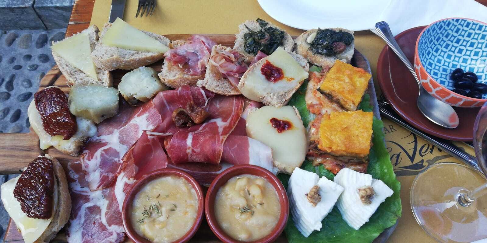Una tabla de embutidos con diferentes carnes, quesos y acompañamientos.