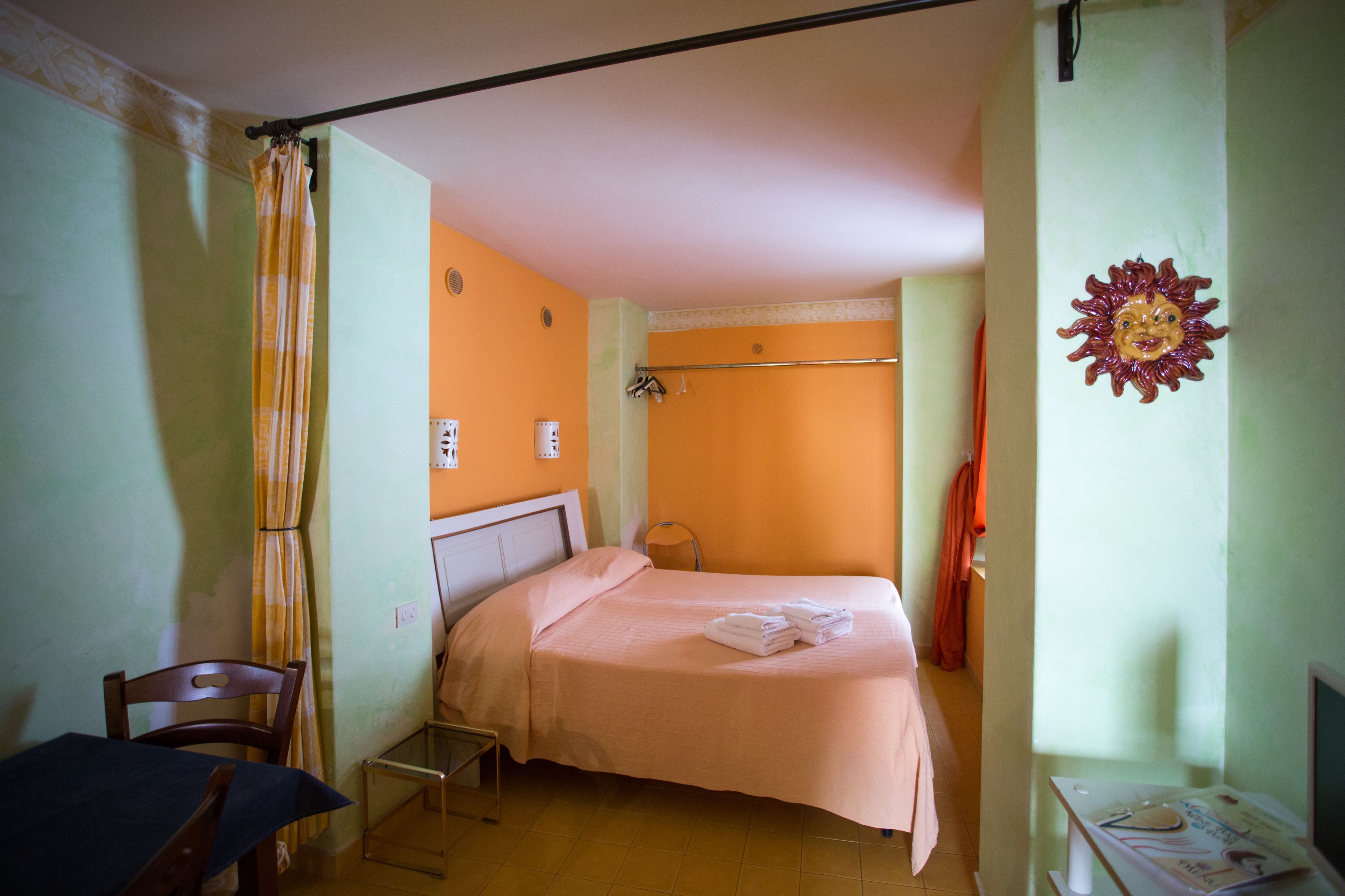 Una habitación pequeña con cama individual, una silla, una mesa y un televisor instalado en la pared.
