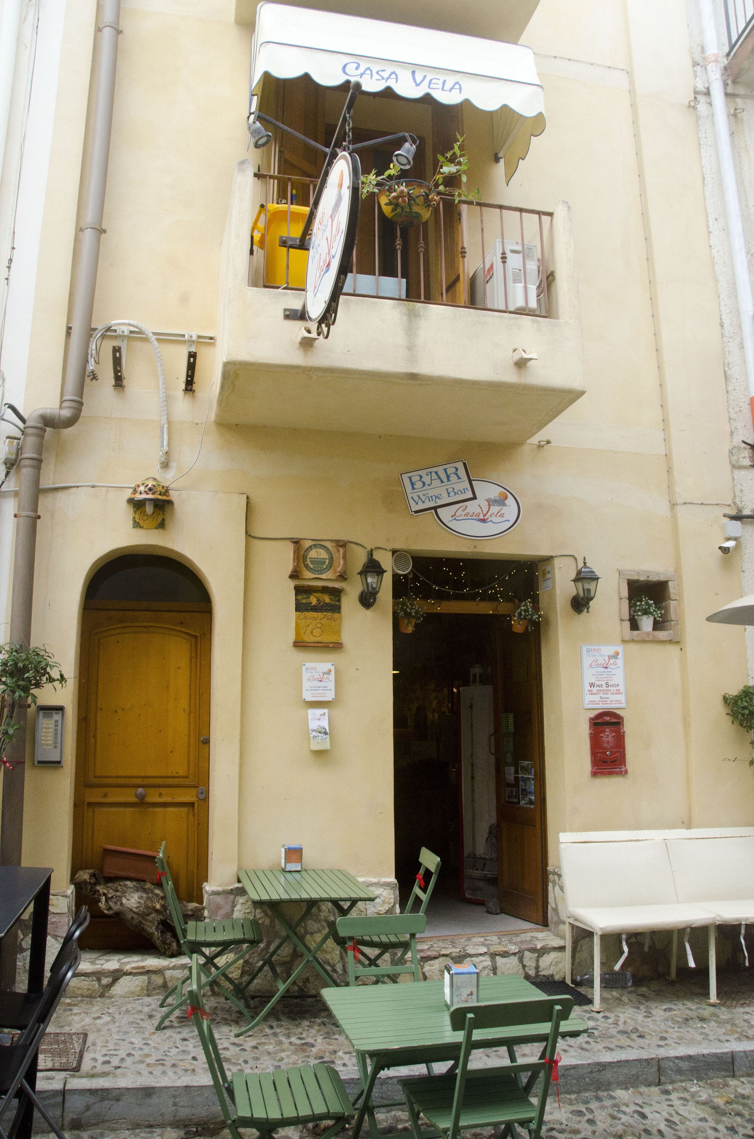 A building with a bar sign, outdoor seating, and a wooden door.