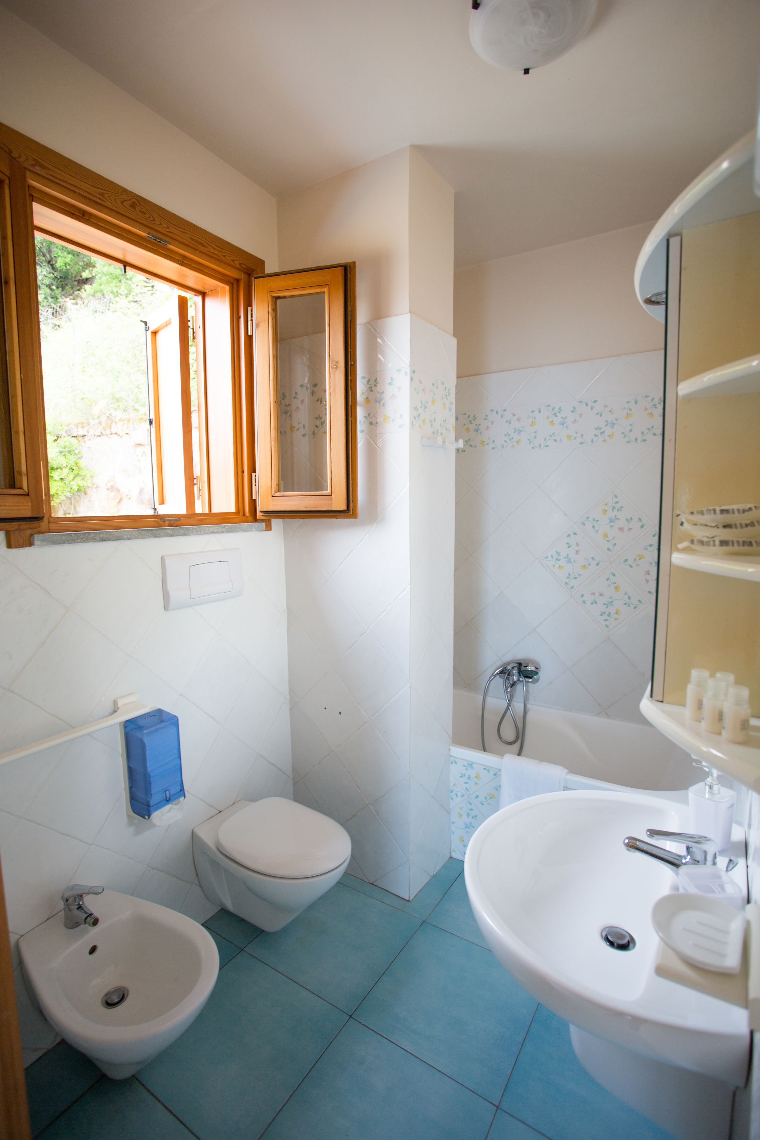 A bathroom with a toilet, bidet, sink, and shower.