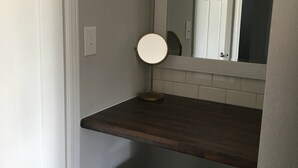 Ein Badezimmer mit einem Holzkosmetikschrank, einem runden Spiegel und einem Mülleimer.