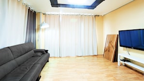 Un salon avec un canapé, un téléviseur et un plancher en bois.