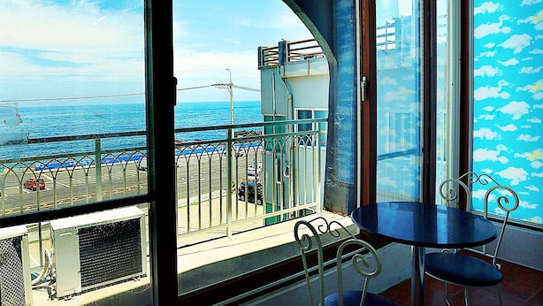 Un balcon avec vue sur la mer, une table avec deux chaises et une rambarde.