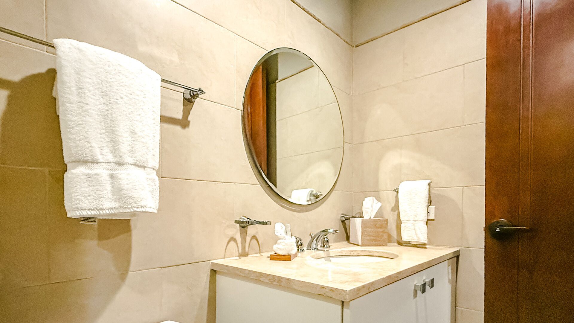 A bathroom with a sink, mirror, towel rack, and a door.
