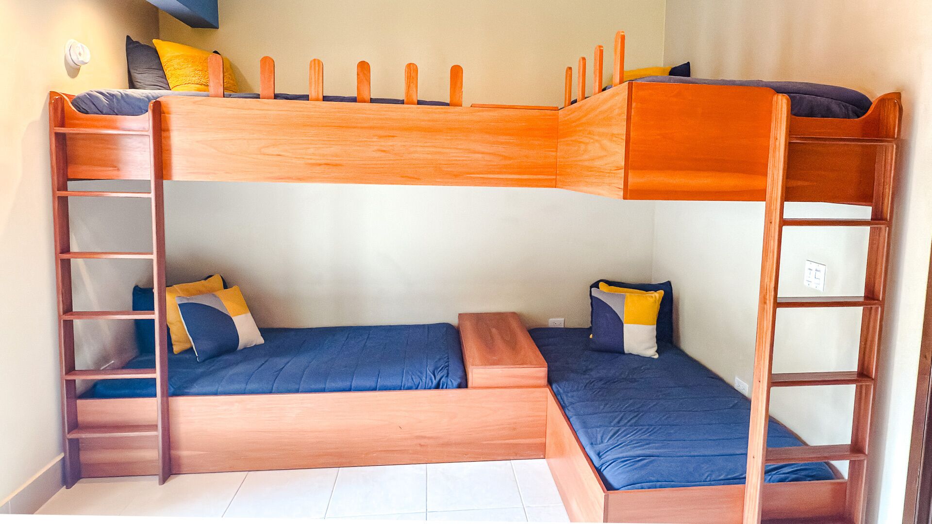 A bunk bed with a wooden ladder, two pillows, and a small bedside table.