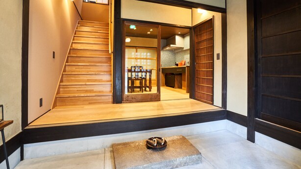 Un interior japonés tradicional con una escalera de madera, suelo de tatami y puertas correderas.
