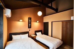 A hotel room with two beds, a wall-mounted air conditioner, and a hanging light fixture.