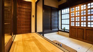 Una habitación tradicional japonesa con suelo de tatami, puertas correderas y vistas a través de un panel shoji.