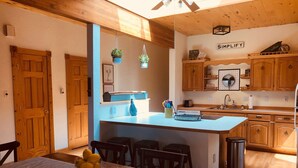 A modern kitchen with wooden cabinets, a central island, and hanging plants. - 2 Bedroom, 1 Bath Townhouse in Historic Downtown Florence! (Florence)