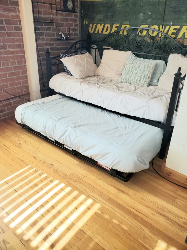 A bed with a mattress and pillows, a brick wall, and a sign with text. - 2 Bedroom, 1 Bath Townhouse in Historic Downtown Florence! (Florence)