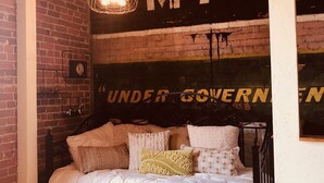 A bedroom with a bed, a brick wall, and a mural with text. - 2 Bedroom, 1 Bath Townhouse in Historic Downtown Florence! (Florence)
