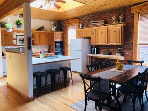 Una cocina con armarios de madera, una isla central y una zona de comedor con sillas y una mesa.