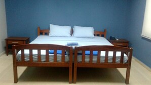 Un dormitorio con cama de madera, dos almohadas, una mesita de noche y una mesilla.