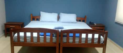 A bedroom with a wooden bed, two pillows, a nightstand, and a bedside table.
