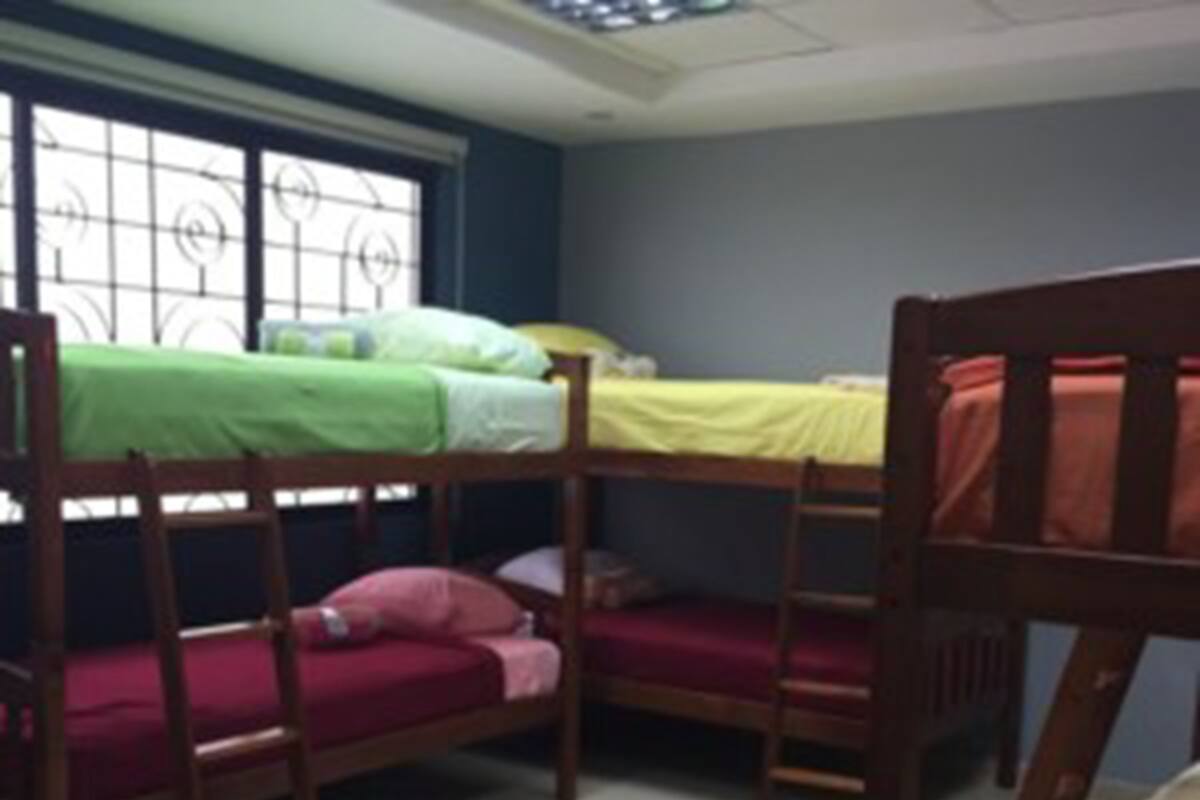 A dormitory room with bunk beds, a window with metal bars, and a tiled floor.