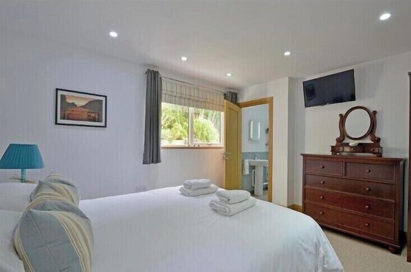 A hotel room with a bed, a dresser, a TV, and a window with curtains. - Luxury ground floor Apartment Sleeps 5 (mevagissey)