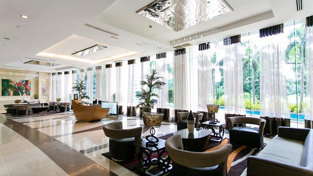 A spacious lobby with a reception desk, seating area, and large windows offering a view of greenery. - 2 Bedroom Bellagio Towers by Stays PH (Taguig)