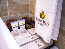 A bathroom with a towel rack holding a towel labeled "Austin Park Hotel."
