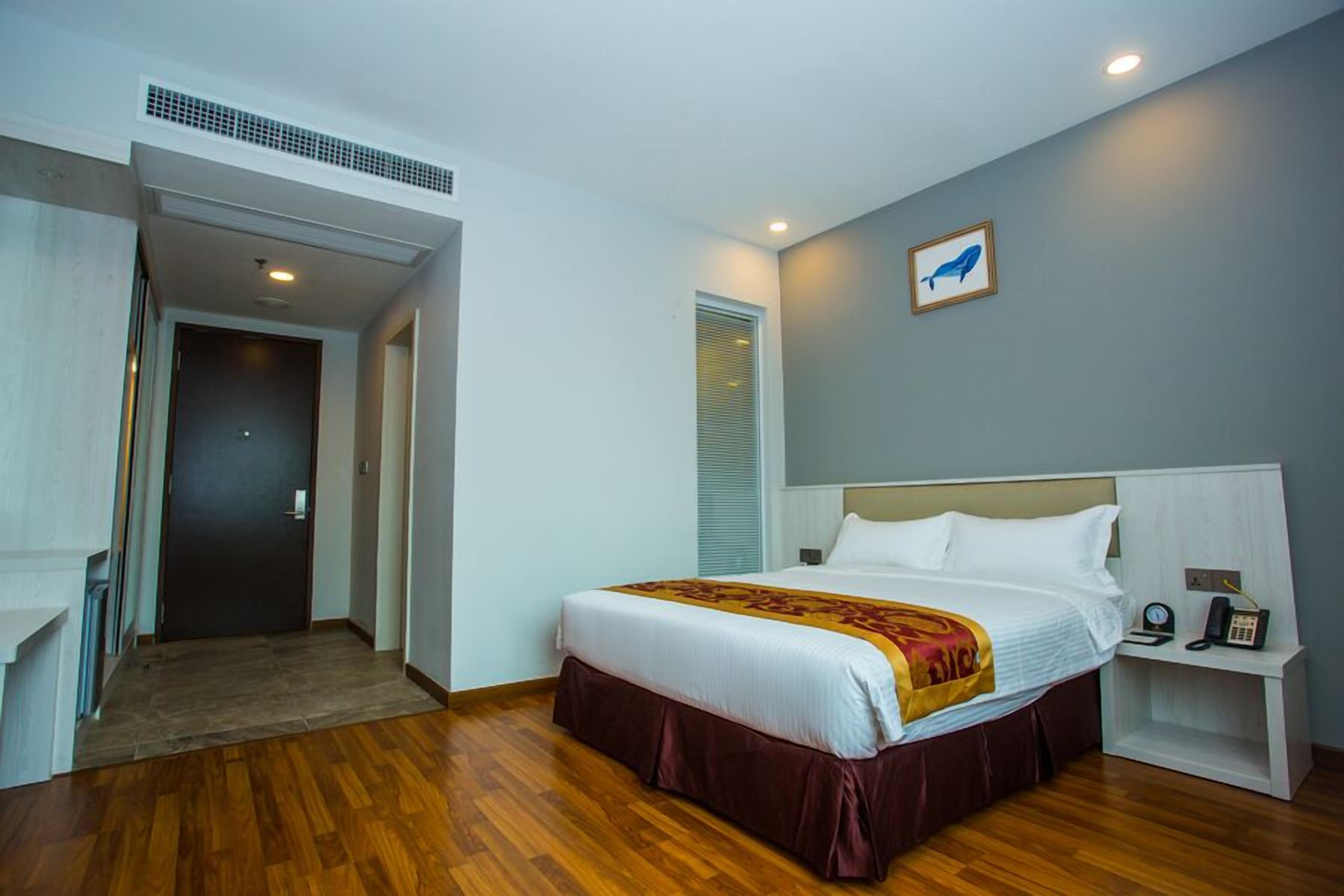 Una habitación de hotel con cama, mesita de noche y un escritorio pequeño con teléfono.