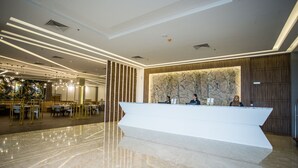 Eine moderne Hotelhalle mit Empfangstresen, einer Sitzecke und einer Wanddekoration.