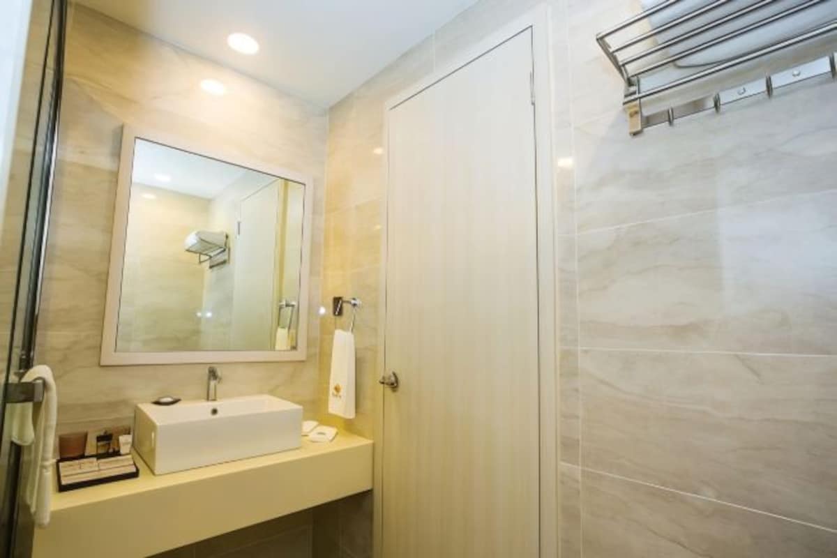 A modern bathroom with a large mirror, a white sink, and a shower area.