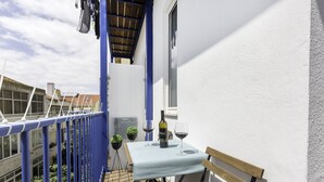 A small outdoor balcony with a table, two potted plants, and a bottle of wine. - Tile House 95, Penha de França (Lisboa)