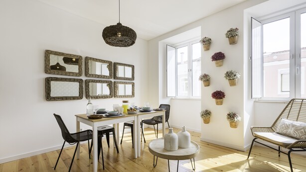 A dining area with a wooden table, black chairs, and a round side table with white vases. - Tile House 95, Penha de França (Lisboa)
