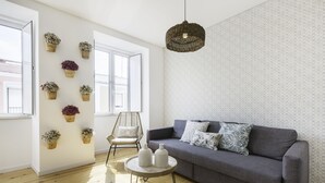 A modern living room with a grey sofa, a round coffee table, and a wicker pendant light. - Tile House 95, Penha de França (Lisboa)